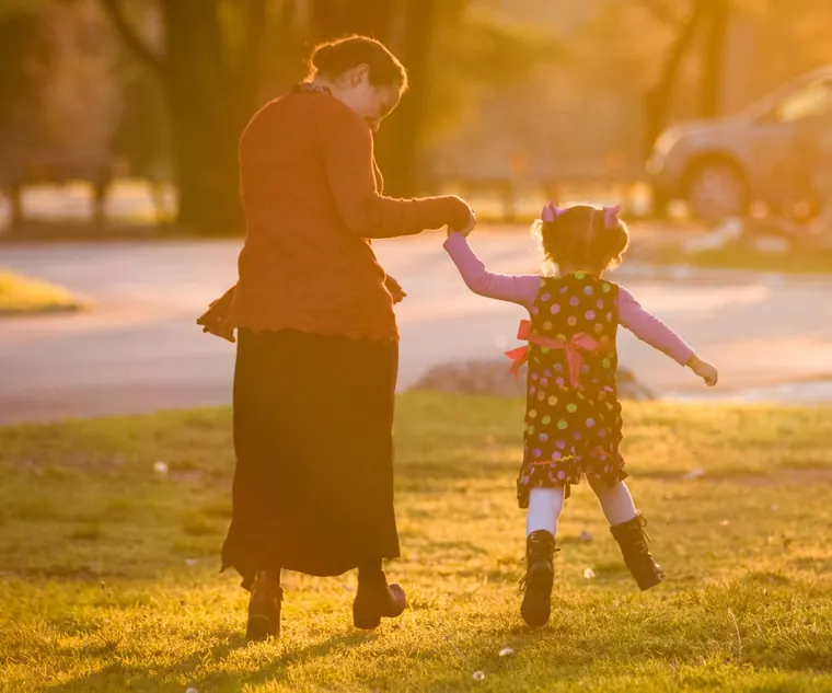 Avó brincando com a neta no parque ao pôr do sol